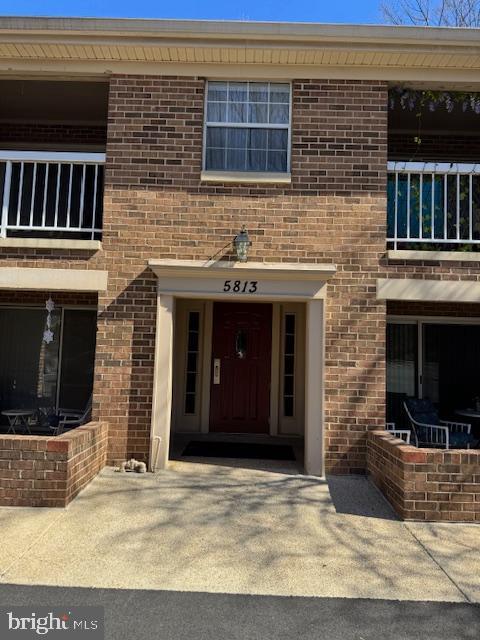 property entrance featuring concrete driveway and brick siding