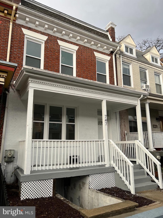 view of property featuring brick siding and a porch