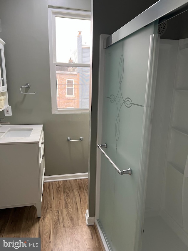 full bathroom with a shower stall, baseboards, wood finished floors, and vanity