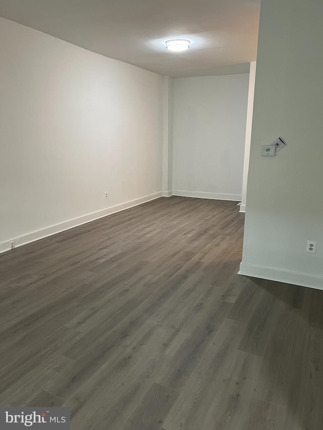 spare room featuring dark wood-type flooring and baseboards