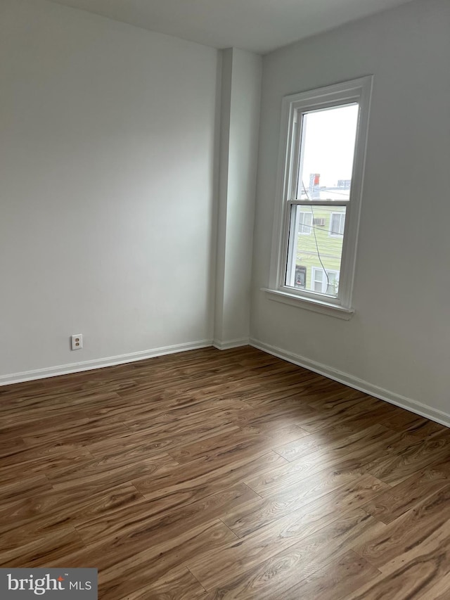 spare room with baseboards and wood finished floors