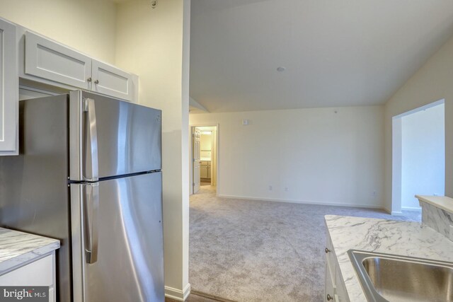 4902 E Pebble Ln Unit E, Milford, DE 19963 - kitchen featuring carpet floors, freestanding refrigerator, vaulted ceiling, white cabinets, and open floor plan