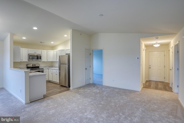 4902 E Pebble Ln Unit E, Milford, DE 19963 - kitchen with stainless steel appliances, light carpet, vaulted ceiling, and white cabinetry