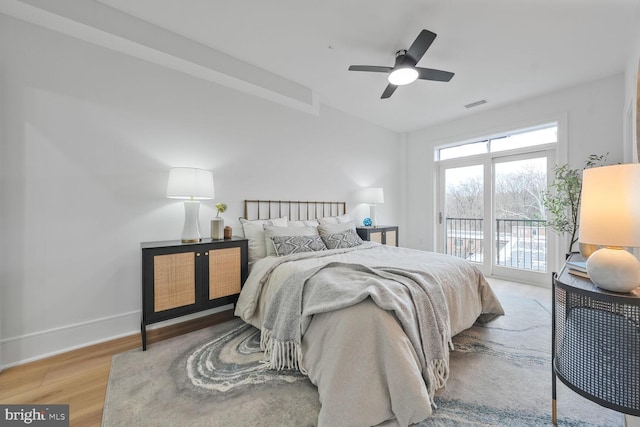 bedroom featuring wood finished floors, a ceiling fan, visible vents, baseboards, and access to outside