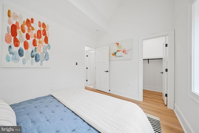 bedroom featuring light wood-type flooring, visible vents, a spacious closet, and baseboards