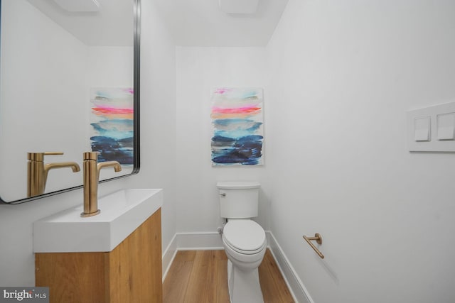 bathroom featuring baseboards, vanity, toilet, and wood finished floors