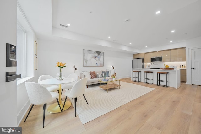 living room with light wood-type flooring, baseboards, visible vents, and recessed lighting