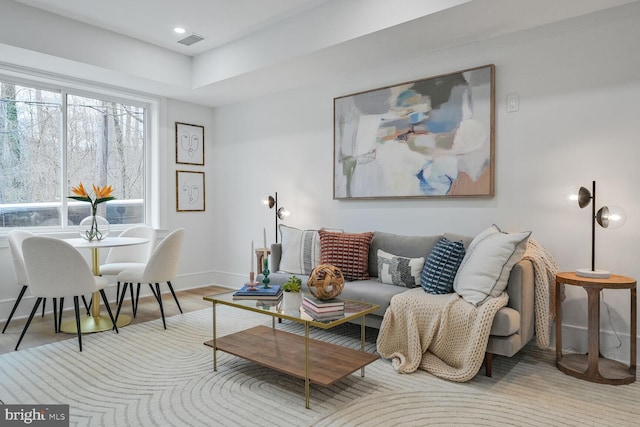 living room with visible vents, baseboards, and wood finished floors