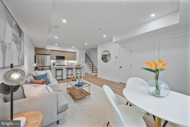 living area featuring stairs, light wood-type flooring, visible vents, and recessed lighting