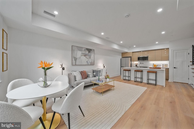 living area with visible vents, baseboards, light wood-style flooring, and recessed lighting