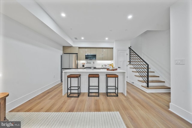 kitchen featuring a breakfast bar area, stainless steel appliances, light wood-style flooring, a sink, and modern cabinets