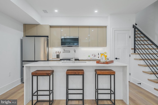 kitchen with stainless steel appliances, cream cabinets, modern cabinets, and light wood-style flooring