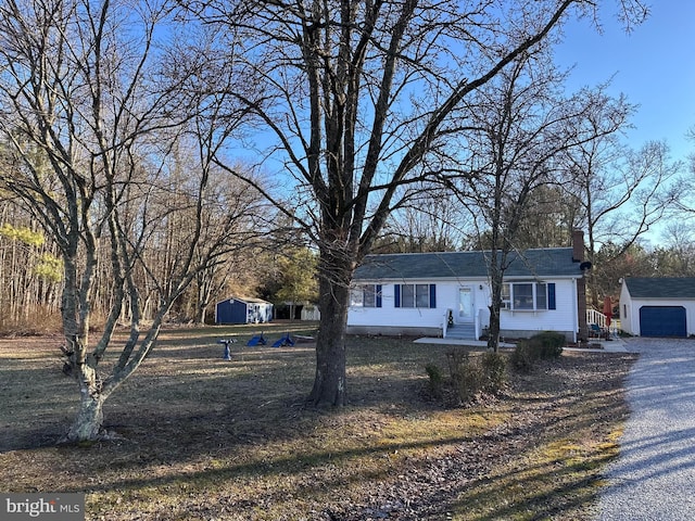 view of front facade with entry steps, a shed, an outdoor structure, a garage, and a chimney