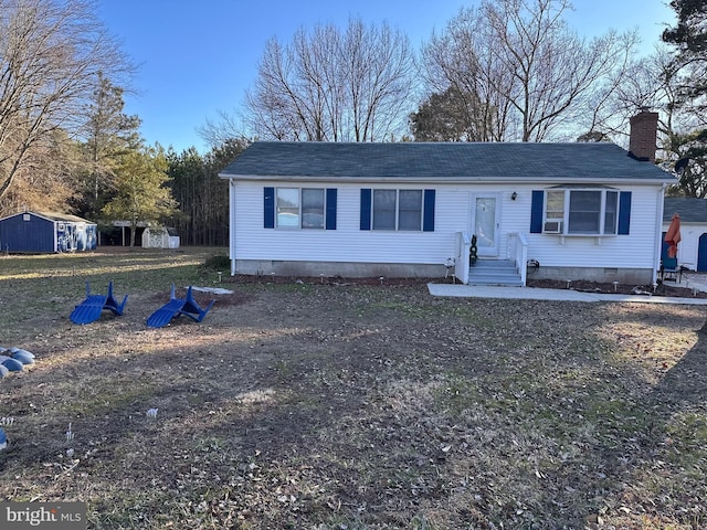 view of front of property featuring entry steps, a storage shed, an outdoor structure, crawl space, and a chimney