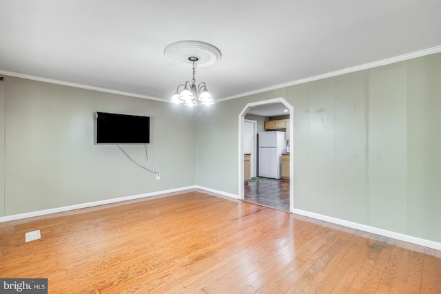 interior space with hardwood / wood-style floors, baseboards, arched walkways, ornamental molding, and a notable chandelier