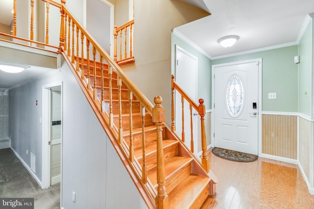 foyer entrance featuring visible vents, wood finished floors, stairs, and ornamental molding