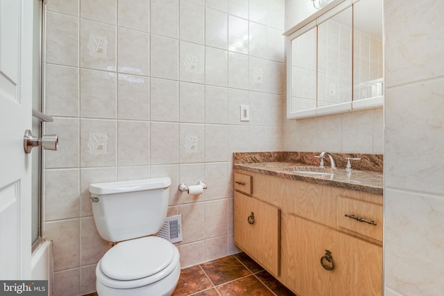 full bathroom with vanity, visible vents, tile walls, toilet, and tile patterned floors