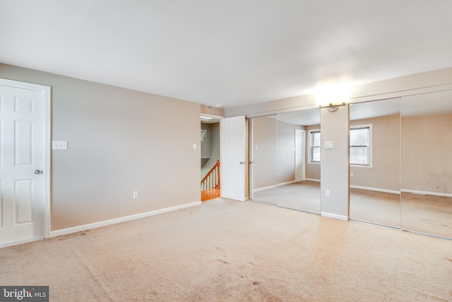 unfurnished bedroom featuring two closets, baseboards, and carpet floors