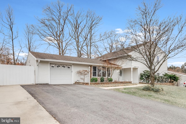 view of front facade featuring aphalt driveway, a shingled roof, a garage, and fence