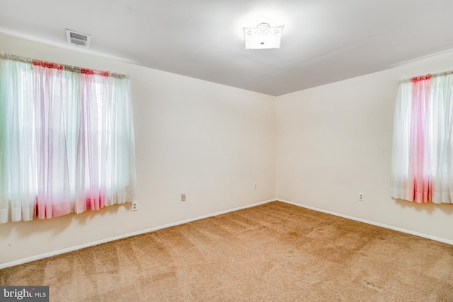 carpeted empty room featuring visible vents, plenty of natural light, and baseboards