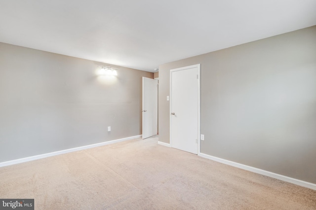 unfurnished room featuring baseboards and light colored carpet