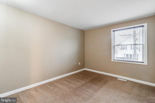 empty room with visible vents, baseboards, and carpet flooring