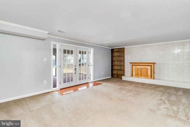 unfurnished living room with visible vents, ornamental molding, a fireplace with raised hearth, french doors, and carpet flooring