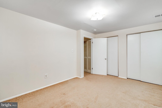 unfurnished bedroom featuring visible vents, carpet flooring, two closets, and baseboards