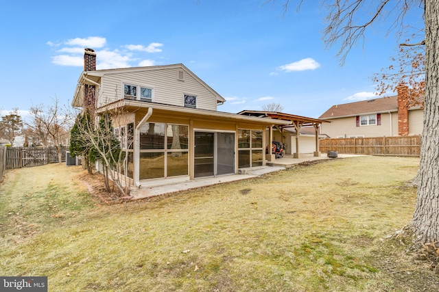 rear view of house with a patio, a yard, a fenced backyard, and a chimney