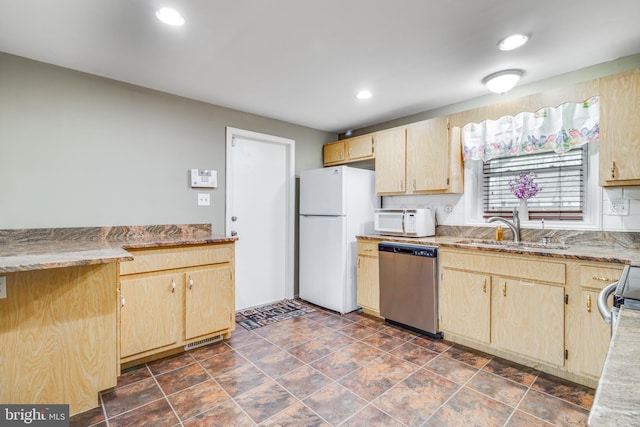 kitchen with light brown cabinets, white appliances, and a sink