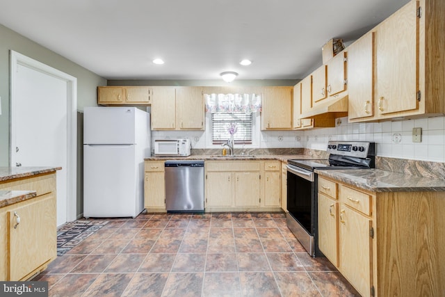 kitchen with light brown cabinets, under cabinet range hood, a sink, tasteful backsplash, and stainless steel appliances