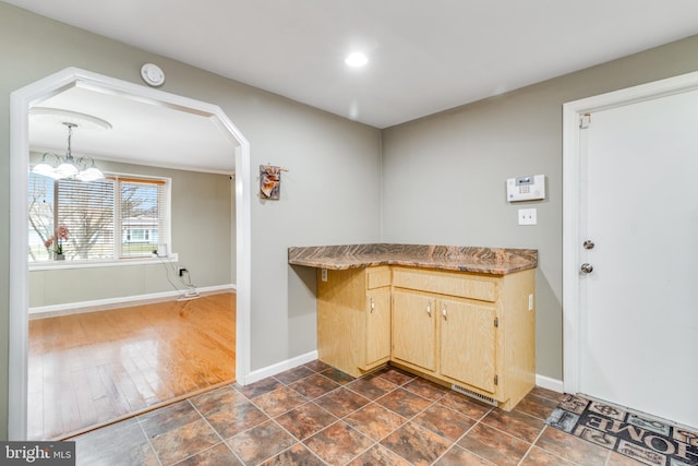 interior space with recessed lighting, baseboards, arched walkways, and light brown cabinetry