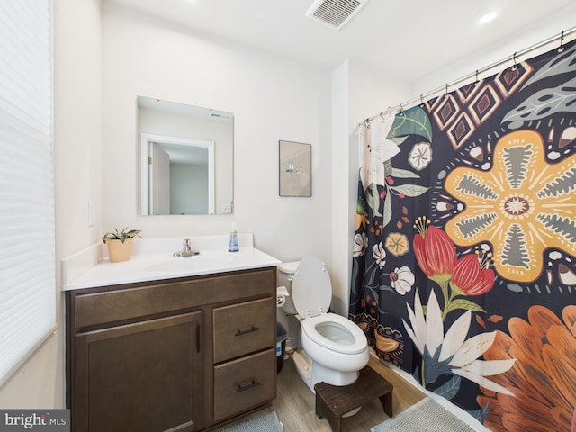 full bath featuring visible vents, a shower with shower curtain, toilet, wood finished floors, and vanity