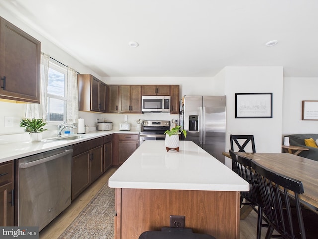 kitchen with a center island, stainless steel appliances, a sink, and light countertops