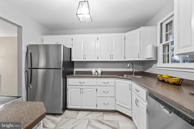 kitchen featuring a sink, dark countertops, appliances with stainless steel finishes, and white cabinetry