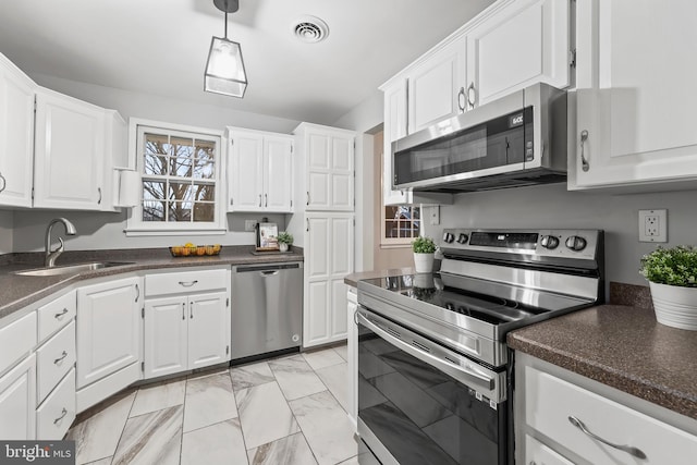 kitchen with stainless steel appliances, dark countertops, visible vents, and white cabinetry