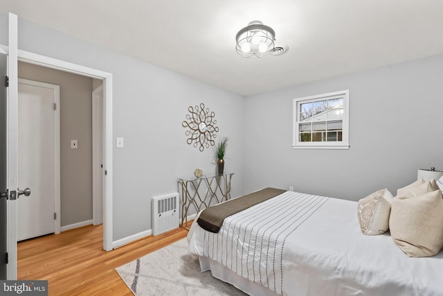 bedroom with heating unit, baseboards, and wood finished floors