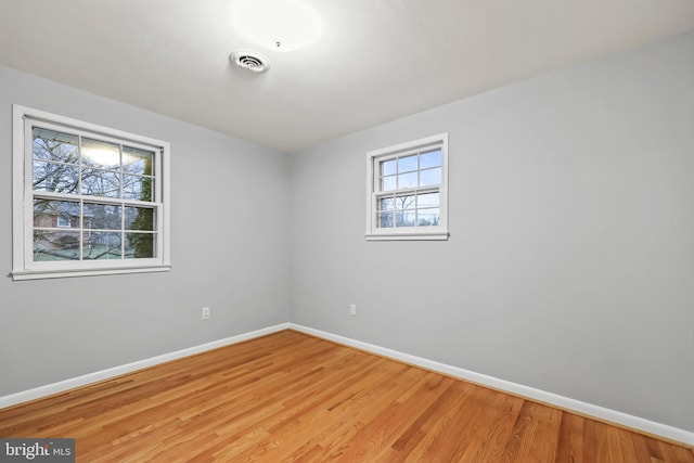 spare room with visible vents, baseboards, and light wood finished floors