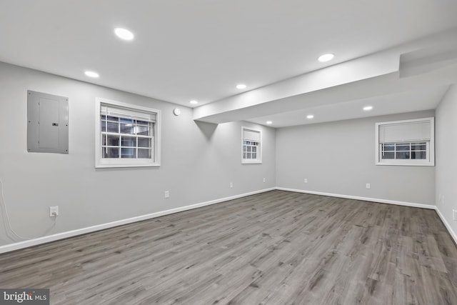 basement with electric panel, wood finished floors, recessed lighting, and baseboards