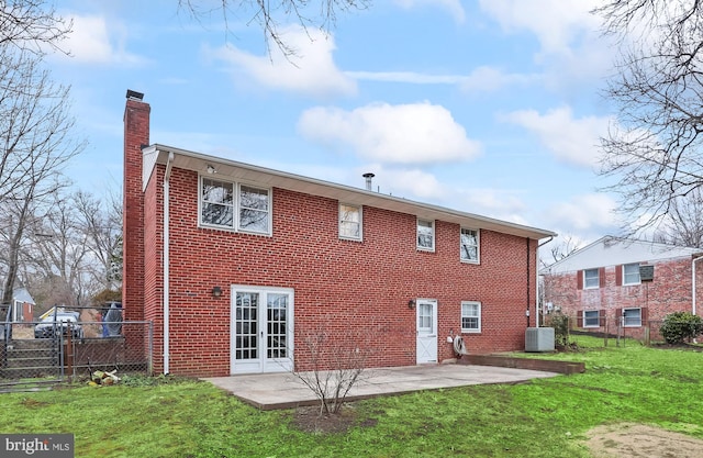 rear view of property with a lawn, fence, french doors, brick siding, and a chimney