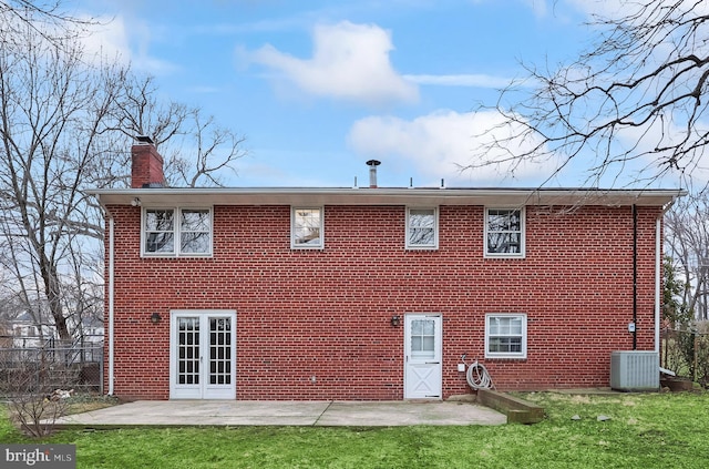 rear view of property with fence, a yard, brick siding, a chimney, and a patio area