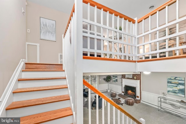 stairway featuring carpet, a towering ceiling, and a fireplace