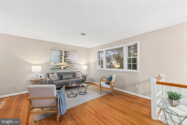 living area featuring visible vents, baseboards, and wood finished floors