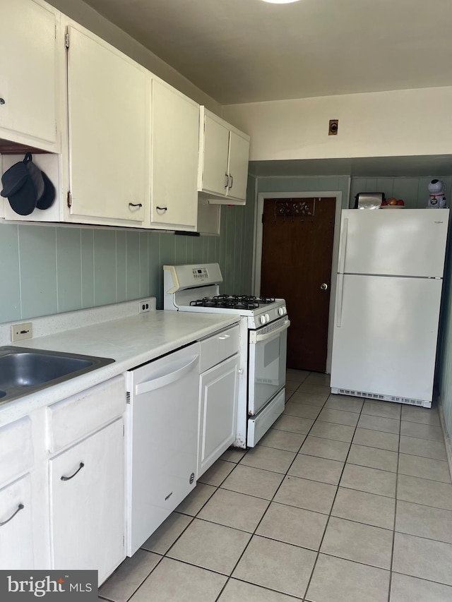 kitchen featuring white appliances, light tile patterned flooring, white cabinets, and light countertops