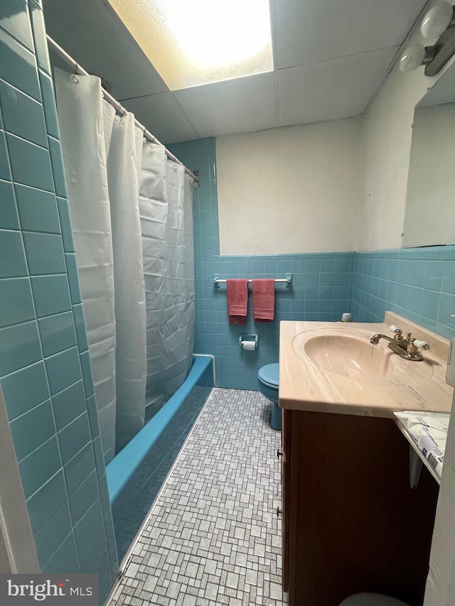 full bathroom featuring tile patterned flooring, tile walls, toilet, shower / tub combo with curtain, and vanity