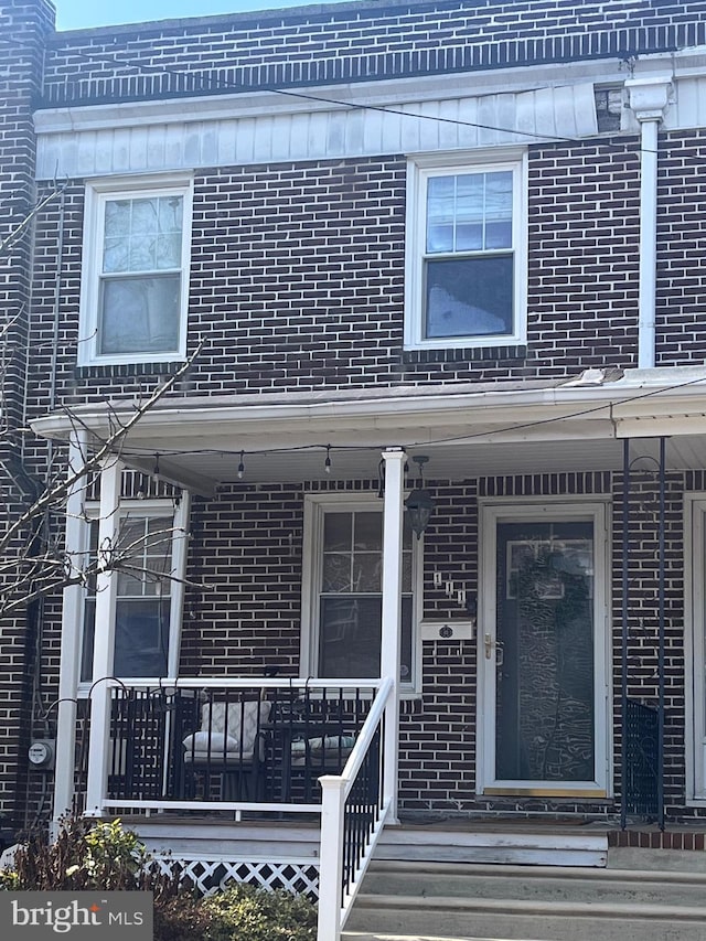 property entrance with brick siding and a porch