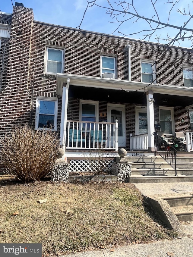 townhome / multi-family property featuring a porch and brick siding