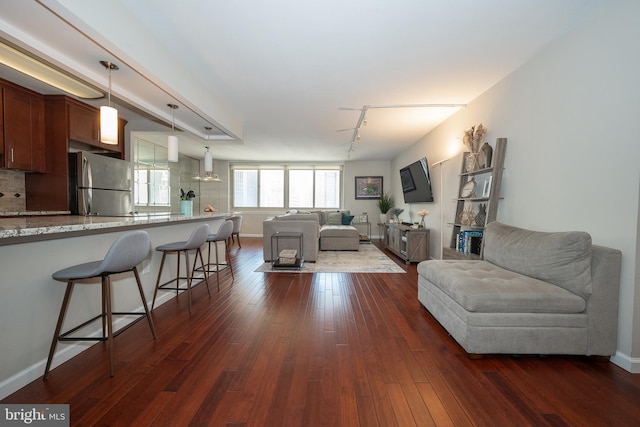 living room featuring baseboards, dark wood-type flooring, and track lighting