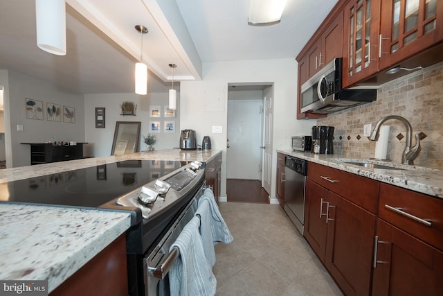 kitchen featuring glass insert cabinets, a sink, light stone countertops, stainless steel appliances, and backsplash