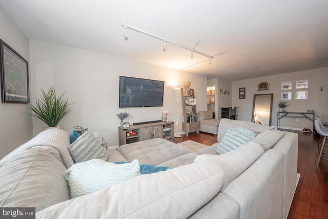 living room featuring dark wood-type flooring, rail lighting, and baseboards